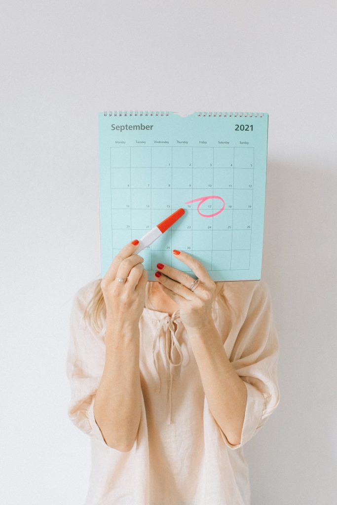 Woman showing the date marked on a calendar with pregnancy testing kit